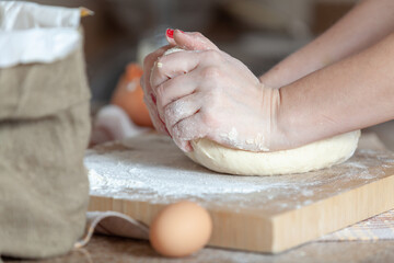 Female hands knead dough on a square board....