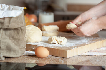 Female hands kneading dough over a board....