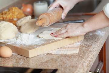 woman hand holds a rolling pin over rolled out dough....