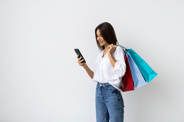 Happy young woman with shopping bags on white background