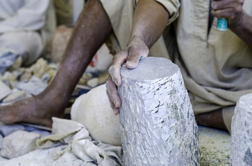 hands of a male Egyptian sculptor while working with a stone alabaster