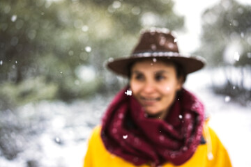 Fototapeta premium Female traveler with yellow rain coat and cowboy hat enjoying snowy day, smiling