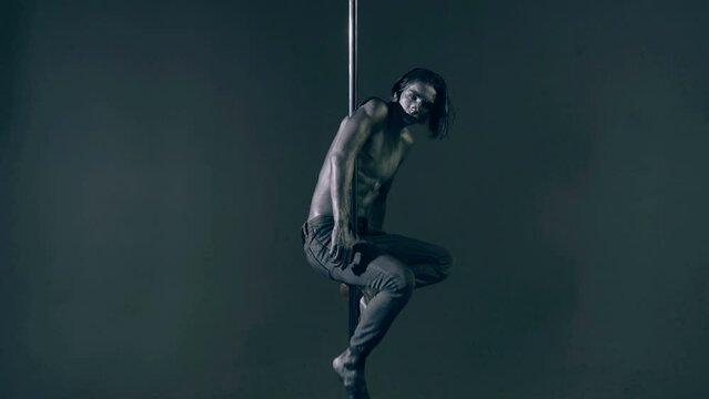 Flexible sexy body of young man. Pole dance. Sexy man exercise pole dance. Fit slim sexy man performs sensual pole dance. Go-go dancer. Strip dancer. Male athlete doing acrobatic trick on pylon.