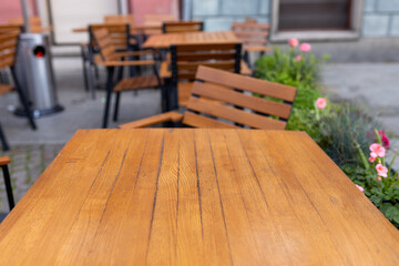 Dining outdoors. Outdoor street cafe tables ready for service. Empty cafe terrace with wooden table and chair. Table of outdoor cafe on sidewalk with colorful plants and flowers