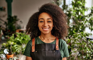 Portrait of adult beautiful sincere genuine African American woman in green t-shirt and apron on...