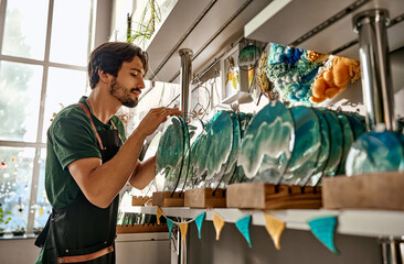 A seller in a decor store counts the painted sea blue color plates made of epoxy resin that lie on...