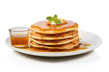 A delicious stack of golden pancakes topped with syrup, a sprig of mint, and a pat of butter, served on a white plate with a side of syrup.