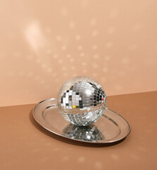 A shining disco ball on a metal tray. Night funny alcohol relax.