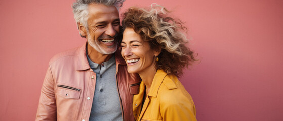 Cheerful senior couple hugging and looking at camera isolated on pink.