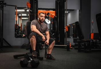 A large bearded man in the gym performs a squat exercise with a barbell. Preparation of a weightlifter for competitions Natural weight gain without the use of steroids. - obrazy, fototapety, plakaty