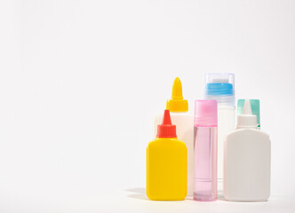 Several tubes of office glue in different colors and shapes on the table. Copy space for text. Stationery set.