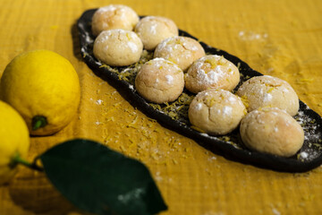 bright yelow lemon crinkle cookies with citrus lemons on kitchen textile napkin, cosy domestic lifestyle , homemade bakery concept