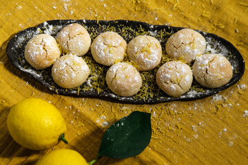 bright yelow lemon crinkle cookies with citrus lemons on kitchen textile napkin, cosy domestic lifestyle , homemade bakery concept