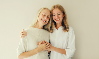 Portrait of happy smiling caucasian middle aged mother or sister and adult daughter together on studio background
