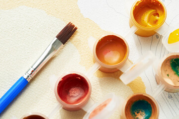 Close up brush and jars with multi-colored acrylic paint for painting by numbers. Top view.