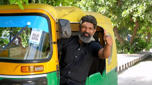 An auto rickshaw driver showing thumbs up - Delhi auto services  transportation  metro city commute  public auto. A man driving an auto rickshaw is posing for the camera - auto ride  auto travel  o...