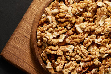 Close-up of a wooden plate of peeled walnut kernels. Top view.