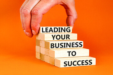 Leading your business to success symbol. Concept words Leading your business to success on wooden blocks. Beautiful orange table orange background. Leading your business to success concept. Copy space