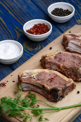 Raw pork ribs with spices and herbs on cutting board on wooden background