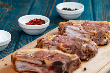 Raw pork ribs with spices and herbs on cutting board on wooden background