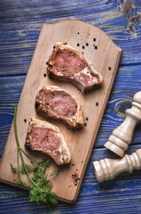 Raw pork ribs with spices and herbs on cutting board on wooden background