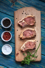 Raw pork ribs with spices and herbs on cutting board on wooden background