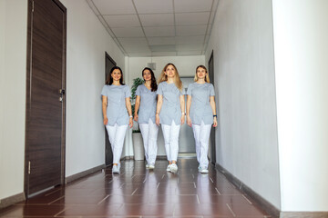 Beautiful smiling female doctors in medical uniform stands near the window in clinic