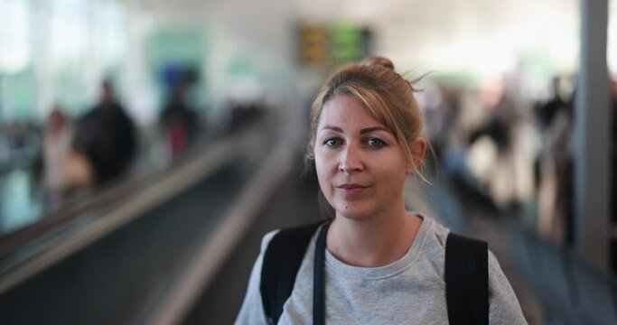 Young blonde woman looking on camera on the walkway at the international airport - Travel concept