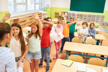 Happy students waving at teacher in class