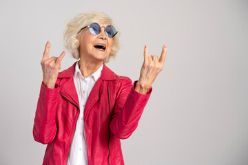 Grey hair excited caucasian woman wearing glasses showing rock gesture