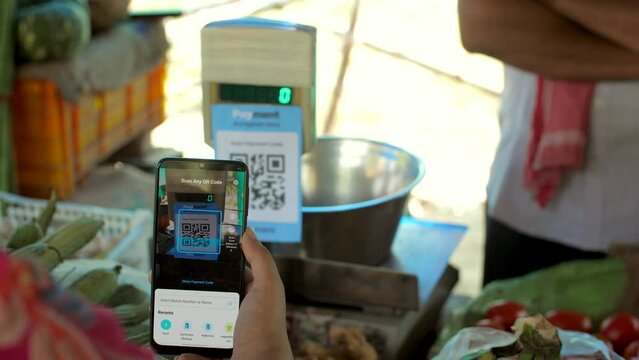 A woman scanning a QR code for making a payment to a vegetable seller - mobile payment  easy access  digital revolution  UPI payment. Shot of a woman making an online payment for the purchase of ve...