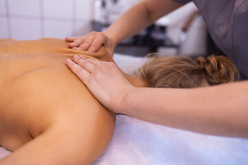 Obraz na płótnie Canvas Happy young caucasian girl getting back massage in spa salon