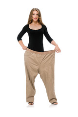 Side view of young woman showing her clothes before and after losing weight, Stunning lady showcases her post-slimming physique in roomy trousers