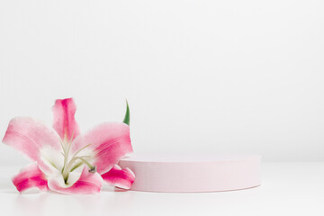 Empty pink podium with lily flower on white background. Aesthetic minimal showcase for spa, perfume, cosmetic and product presentation