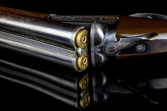 Vintage Side by Side Shotgun with Cartridges on a Reflective Black Surface