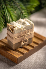 A piece of fragrant natural soap on an organic wooden soap dish against the background of green...