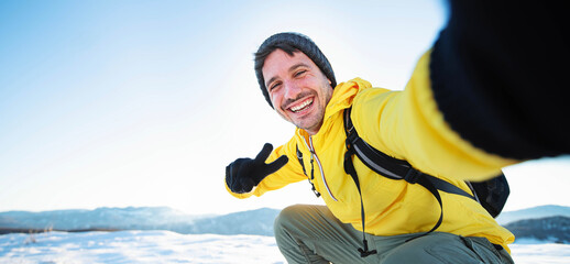 Young man wearing winter clothes taking selfie picture in winter snow mountain - Happy guy with...