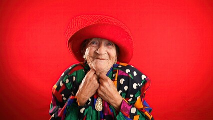 Portrait of funny elderly senior old woman with no teeth and wrinkled skin looks at camera gives great idea gesture showing explosion of thinking posing isolated on red background