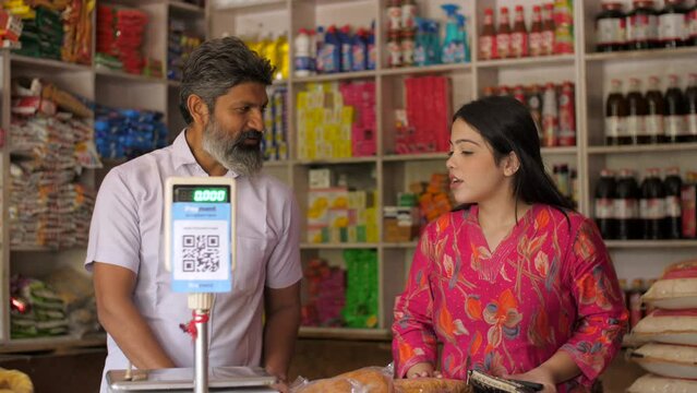 A beautiful Indian woman purchasing groceries at the neighbourhood store - consumer products  price and consumer index  inflation  Indian store. A vendor selling essential goods - FMCG products  fa...