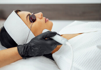 Closeup of face of beautiful relaxing girl undergoing hardware cosmetology procedure in spa