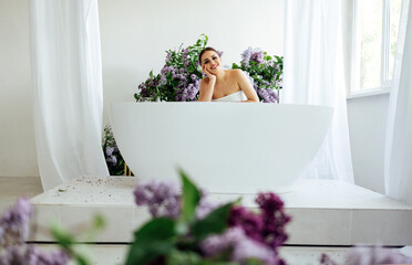 Obraz na płótnie Canvas Woman folding arms on a hot tub and placing her chin on them while sitting with smile,