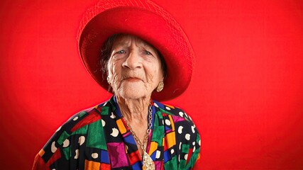 Unhappy displeased fisheye portrait caricature of funny elderly woman saying NO with red hat isolated on red background.