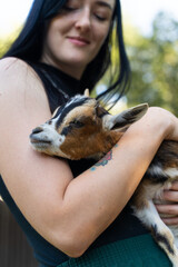 A small cute goat in a woman's arms