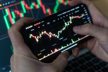 Smartphone with mobile application cryptocurrency wallet. A man analyzes the price chart for bitcoin in a mobile application. The concept of cryptocurrency trading