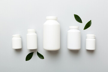 supplement pills with medicine bottle health care and medical top view. Vitamin tablets. Top view mockup bottle for pills and vitamins with green leaves, natural organic bio supplement, copy space