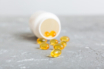 Soft gels pills with Omega-3 oil spilling out of pill bottle close-up. Gel capsules bottle white...