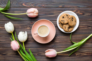 Cup of coffee mug with coffee, cookies and tulips on a colored background. Greeting spring card top view