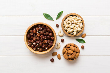 Assortment of nuts in wooden bowl on colored table. Cashew, hazelnuts, walnuts, almonds. Mix of nuts Top view with copy space