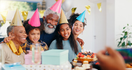 Cake, happy and family at birthday party celebration together at modern house with candles. Smile, excited and young children with African father and grandparents with hats for photograph at home.