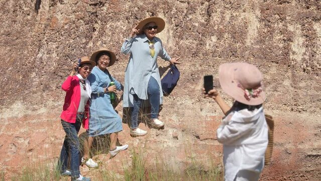 Group of senior aging women hiking walking exercising together on holiday vacation, healthy elderly pensioner females happy talking traveling enjoy outdoors activities, smartphone technology selfies
